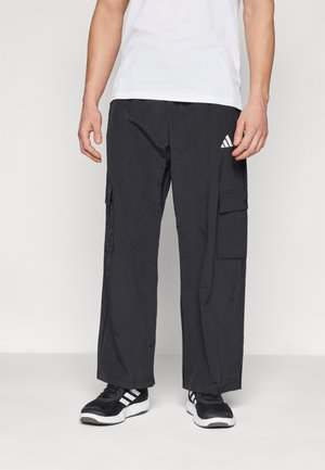 Svarta cargobyxor i lätt tyg, med sidofickor och resårmidja. Kombinerat med en vit idrottströja och svarta sneakers.