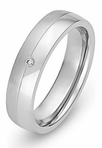 Anello in metallo color argento con una finitura spazzolata e una striscia lucidata, caratterizzato da un piccolo diamante rotondo incastonato.