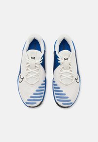 Baskets de sport blanches et bleues avec une tige en maille, présentant un design texturé, des lacets ronds et des accents noirs.