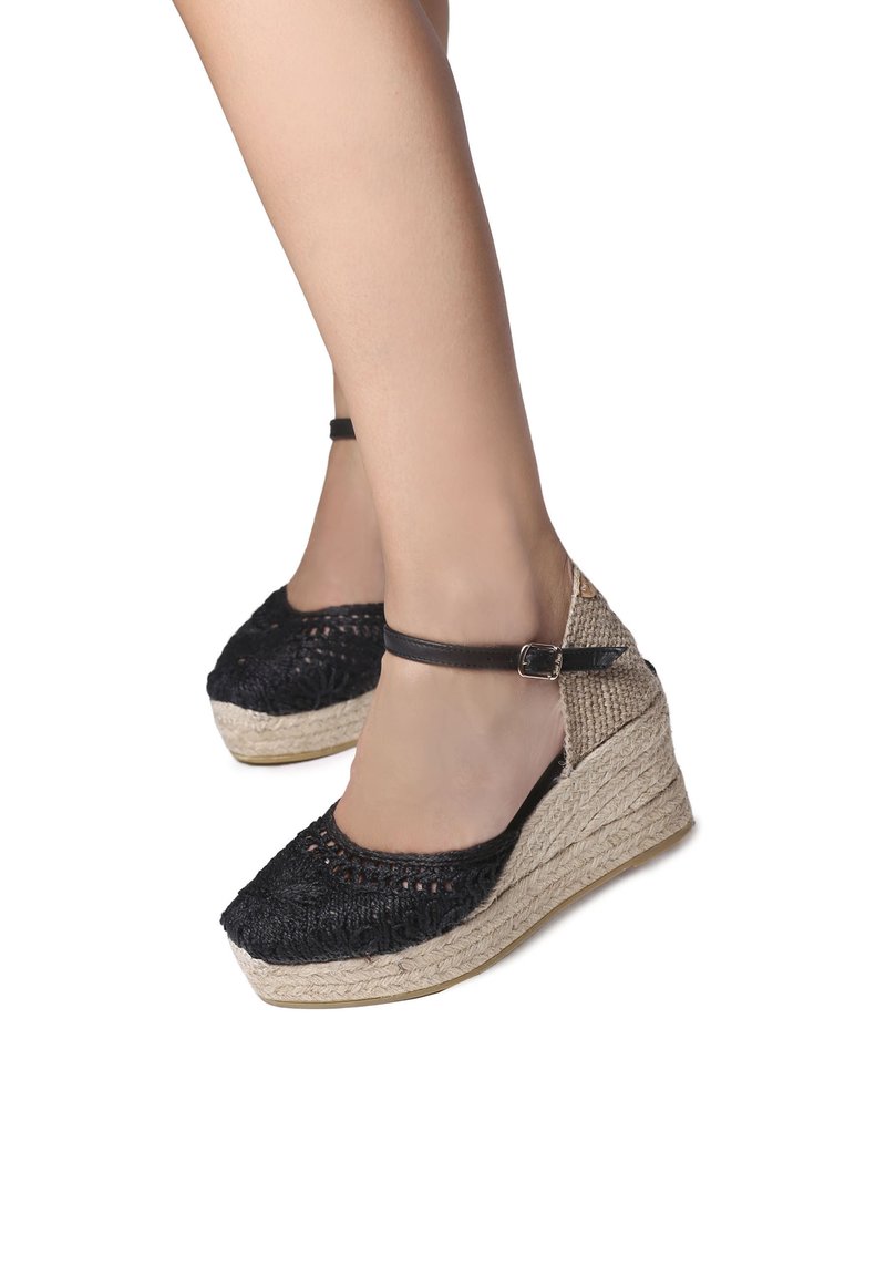 Černé tkané espadrilové wedge podpatky s jutu, s kotníkovým páskem a otevřenou špičkou. Texturovaný svršek s přírodním vzhledem.