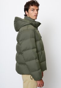 Green puffy jacket with a hood, featuring quilted sections, a front zipper, and elastic cuffs. Smooth fabric with a matte finish.