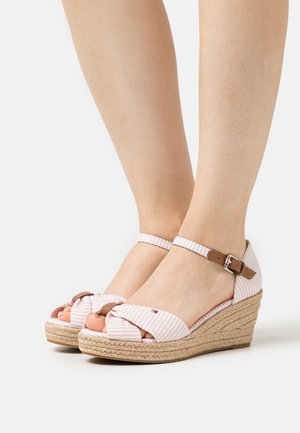 Sandali con zeppa in tessuto a righe rosa e bianche, con una fascetta per le dita annodata e una cinghia alla caviglia marrone con fibbia. Piattaforma avvolta in juta.