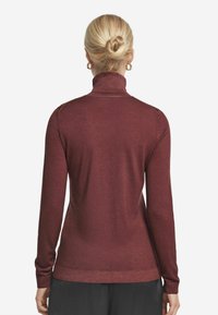 Mörkröd polotröja med långa ärmar. Mjuk textur och smal passform, med ribbad krage och manschetter.