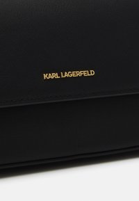 Black leather bag featuring a smooth texture, with a gold "KARL LAGERFELD" logo displayed prominently on the front.