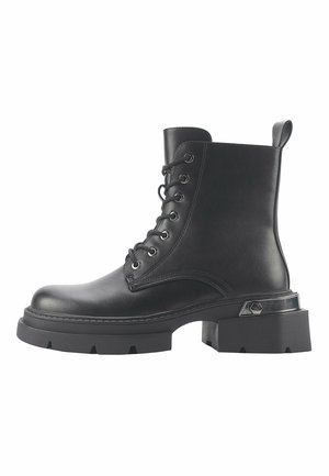 Zwarte leren enkellaars met een ronde neus, vetersluiting, chunky zool en contrasterende zilverkleurige hardware detail op de hak.