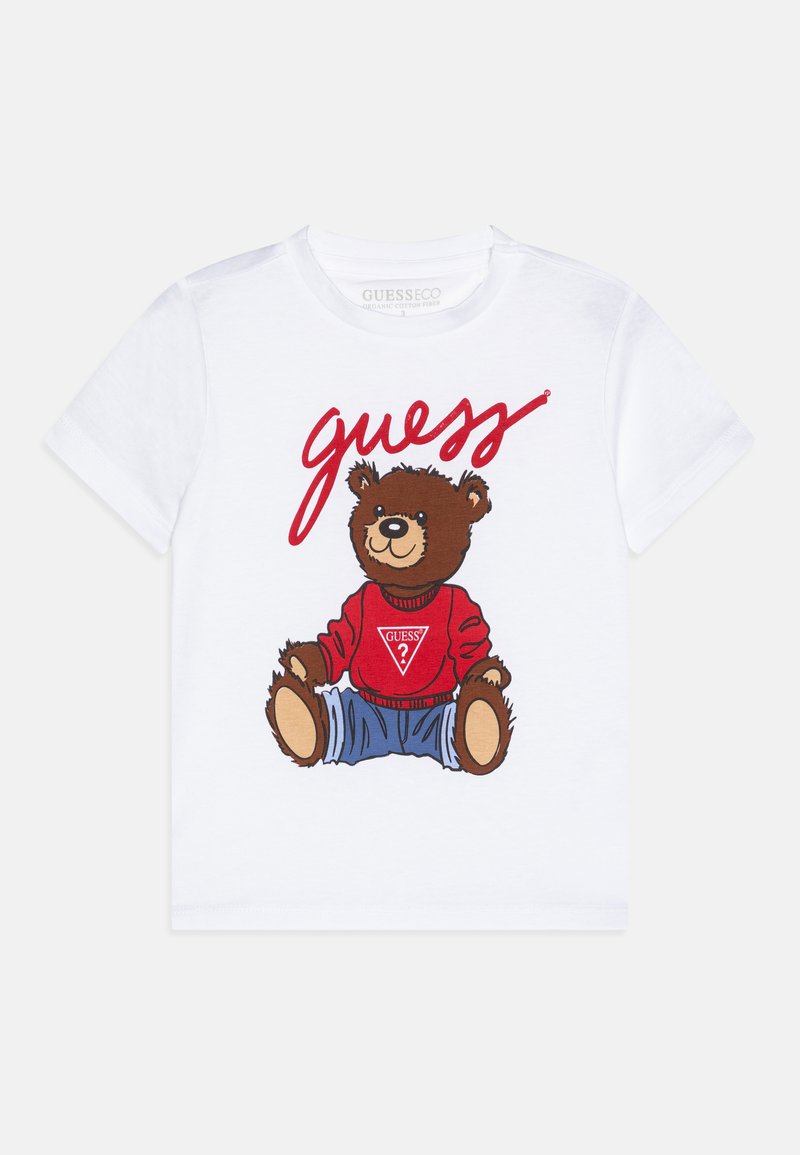 T-shirt en coton blanc avec une illustration d'ours portant une chemise rouge avec le logo "GUESS", un jean bleu et des traits du visage détaillés.