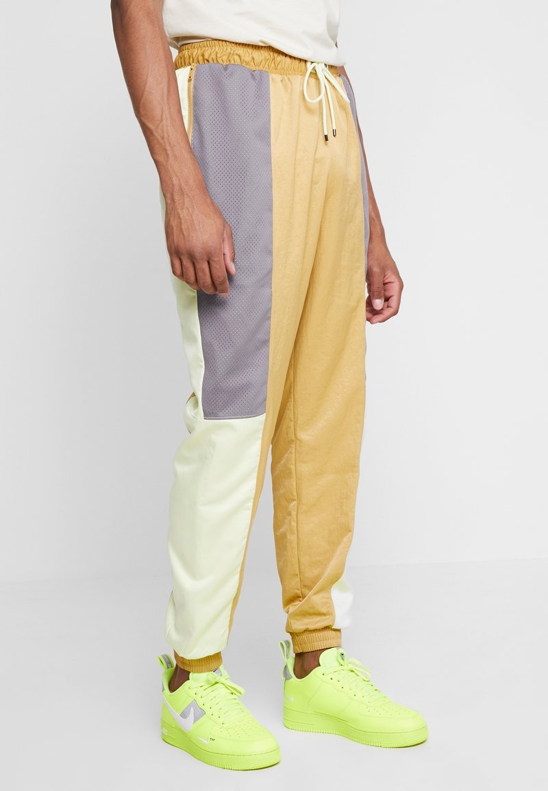 Herren-Jogginghosen mit gelben, grauen und weißen Einsätzen, gefertigt aus leichtem Material mit einem elastischen Bund und schlanker Passform.