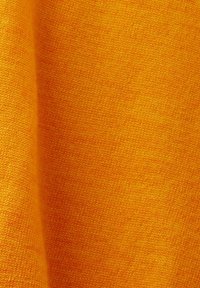 Gros plan d'un tissu tricoté orange doux montrant une texture fine et de petits plis.