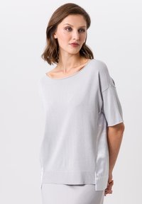 Haut à manches courtes gris clair en tissu satiné, à coupe ample, avec un col large et des accents en satin sur les côtés. Texture tricotée avec base côtelée.