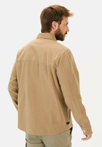Khaki knoop-overhemd met een kraag, lange mouwen, rechte snit en een klein logotag aan de onderkant links. Geweven stof.