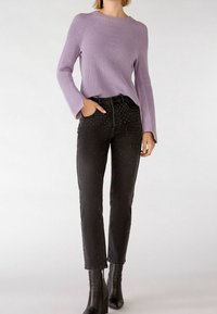 Lavender ribbed knit sweater with bell sleeves paired with black jeans adorned with silver and green studs, worn with black ankle boots.