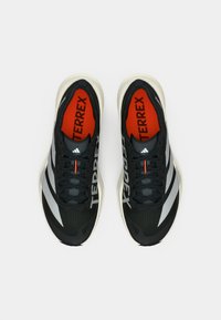 Μαύρα αθλητικά παπούτσια με γκρι λεπτομέρειες και λευκή σόλα. Διαθέτουν υφασμένο επάνω μέρος, επενδυμένο πέλμα και έντονη κόκκινη εσωτερική σόλα με την επωνυμία "TERREX".