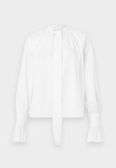 White long-sleeve blouse in cotton with a mandarin collar, tie detail, and gathered sleeve cuffs. Smooth texture and minimalistic design.