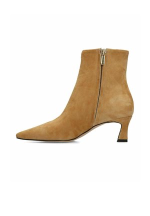 Bottine en daim beige avec bout pointu, talon kitten de hauteur moyenne et fermeture éclair latérale.