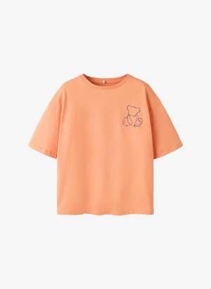 Pfirsichfarbenes T-Shirt mit kurzen Ärmeln und einer einfachen, dunklen Linienzeichnung eines Teddybären auf der oberen linken Brust.