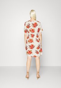 Vestido floral em bege com flores vermelhas e laranjas; mangas curtas, corte solto, comprimento até o joelho e cintura ajustada. Acentuado com uma leve textura.