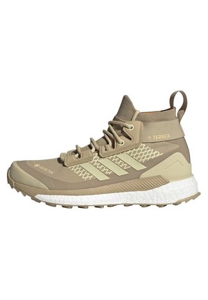 Zapato de senderismo Adidas Terrex de caña alta en color beige con Gore-Tex, entresuela texturizada, cordones y suela robusta para uso al aire libre.