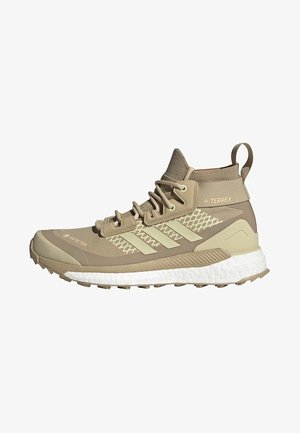 Chaussure de randonnée montante Adidas Terrex beige avec Gore-Tex, semelle intermédiaire texturée, lacets et semelle extérieure robuste pour une utilisation en plein air.