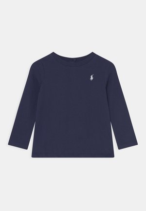 Granatowa koszulka z długim rękawem i okrągłym dekoltem, z małym białym wyszywanym logo gracza polo po lewej stronie klatki piersiowej.