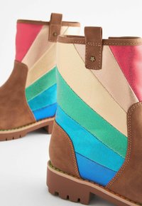 Botas de tobillo marrones con un diseño de chevron arcoíris que incluye acentos de cuero en rosa, beige, verde, azul y azul intenso. Incluye una lengüeta cosida.