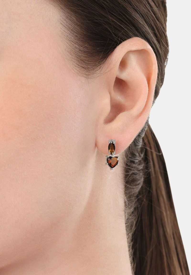 Orecchini color oro con due gemme marroni a forma di goccia e cuore, con decorazioni in argento. Design leggero.