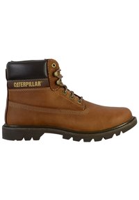 Ruske kožne radne čizme s crnim podstavljenim ovratnikom, metalnim očicama i čvrstim gumenenim đonom. Sadrži Caterpillar logo sa strane.