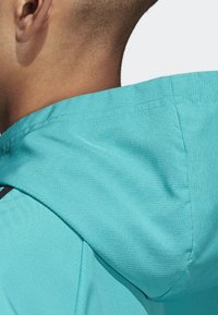 Turquoise hoodie met een gestructureerde stof, waarop de naden en een zwarte accent te zien zijn. Vangt de achterkant en zijkant van de capuchon.