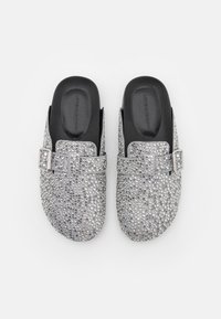 Silberne Clogs mit abgerundeter Form, verziert mit Strasssteinen, ausgestattet mit einem Riemen und einer schwarzen gepolsterten Innensohle für Komfort.