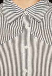 Striped shirt featuring a classic collar and button placket with white and navy vertical stripes; smooth fabric texture.
