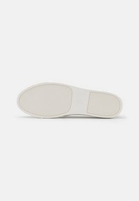 Weiße Sneaker-Sohle mit flachem Design, strukturiertem Gummioberfläche und vertikalen Rillen für Grip. Minimale Markenkennzeichnung vorhanden.