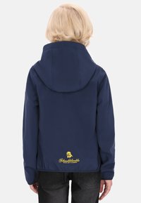 Sötétkék dzseki, illeszkedő kapucnival, melynek hátán egy sárga logó található. Simára, könnyű anyagból készült.