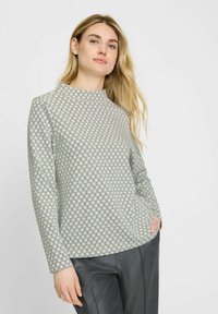 Langärmliges Oberteil mit hohem Kragen, aus leichtem Stoff mit einem geometrischen Muster in Grau und Schwarz. Lässige Passform mit Seitentaschen.