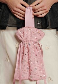 Saco rosa com cordão feito de tecido macio, adornado com florais intricados e aplicações de lantejoulas, com uma alça de cetim.