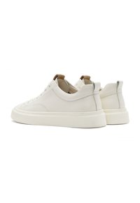 Baskets en cuir blanc avec une finition lisse, dotées d'un système de laçage tonal, d'une semelle en caoutchouc épaisse et d'un accent en cuir marron au niveau du talon.