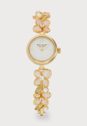 Montre dorée avec un cadran blanc, bracelet floral au design de pétales roses, perles et accents scintillants. Forme globale élégante.