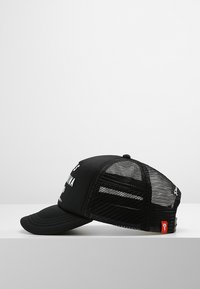 Cappellino nero con un pannello frontale solido e un retro in rete. Ha una visiera curva e un'etichetta rossa sul lato. Testo stampato sulla parte anteriore.