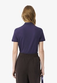 Polo shirt blu navy realizzato in un tessuto morbido, con maniche corte e colletto classico, abbinato a pantaloni scuri con vita elastica. Senza motivi o dettagli visibili.