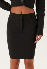 Svart blyertskjol i slät väv; har en skräddarsydd passform, midja med bältesöglor och framfickor.