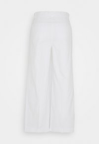 Pantalons larges blancs à taille haute et poches arrières, présentés sur un fond blanc uni.