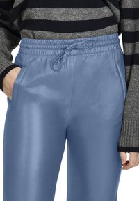 Lichtblauwe synthetische joggingbroek met een gladde textuur, elastische tailleband en verstelbare strik. Heeft zijzakken en een getailleerd ontwerp.