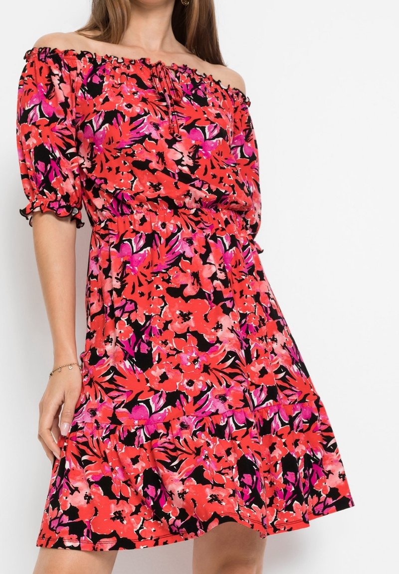 Šaty se zavazováním přes ramena s květinovým vzorem v červené, růžové a černé barvě. Vyrobené z lehké látky, s přiléhavým pasem a vrstveným lemem.