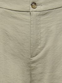 Pantalon en lin beige avec une fermeture par bouton et un détail de couture apparente à l'avant.