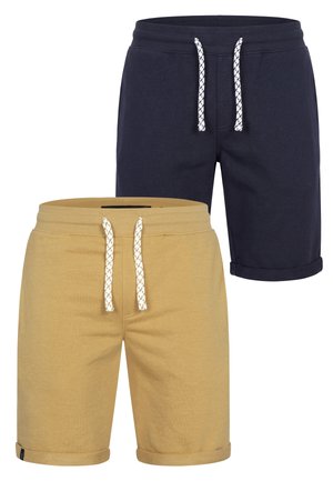 Twee paar casual shorts met trekkoorden, één beige en één donker marineblauw, beide met opgerolde zomen en voorzakken.