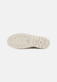 Semelle de sneaker blanche avec un motif texturé. Présente des sections plates et des rainures pour l'adhérence. Six trous pour la circulation de l'air près de la zone des orteils.