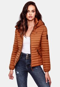 Rudas pūkinis džemperis su horizontaliais siuvinėjimais, su kapišonu ir užtrauktuko kišenėmis. Sujungtas su tamsiais džinsais su mygtukų akcentais.