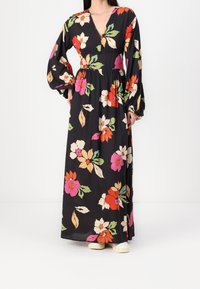 Svart maxiklänning med lång ärm och V-ringning, med färgglada blommönster i röd, rosa och grön. Lätt, flödande tyg.