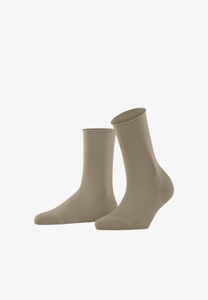 Chaussettes beiges en tissu doux et extensible. Elles ont une texture lisse, un orteil renforcé et un design classique de hauteur crew.