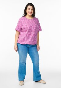 Blusa rosa a maniche corte con motivo floreale, abbinata a jeans larghi azzurri e ballerine beige. Tessuto morbido, vestibilità rilassata, scollo rotondo.