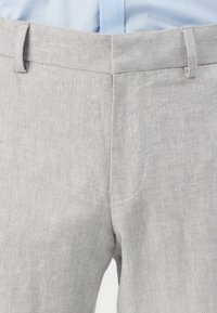 Γκρι παντελόνι herringbone με ίσια γραμμή και διακριτό υφασμάτινο σχέδιο, διαθέτοντας μέση με θηλιές για ζώνη και φερμουάρ.