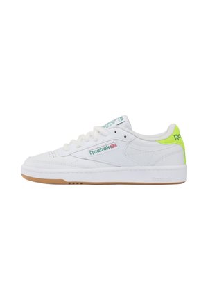 Witte lage Reebok-sneaker met groen logo, detail van de Union Jack-vlag en neongeel hielbandje, voorzien van gumzool en witte veters.